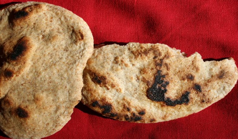 Home baked unleavened flour and water flatbread on a red tablecloth.