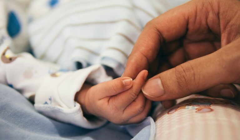 Adult hand holding baby hand