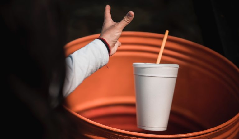 A woman throwing a styrofoam cup away