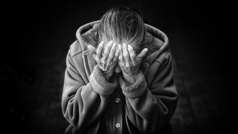 Elderly woman with head in hands