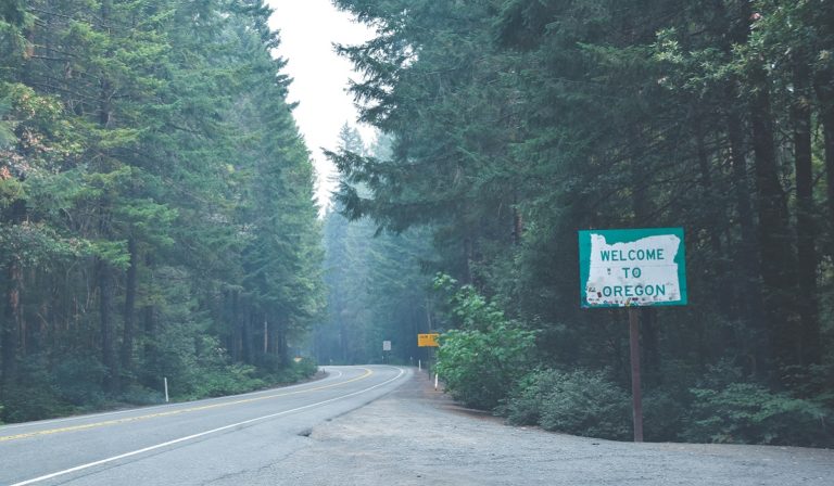 Welcome to Oregon sign amidst evergreen trees