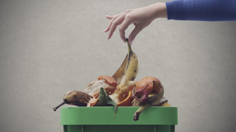 Woman putting organic waste in the compost bin