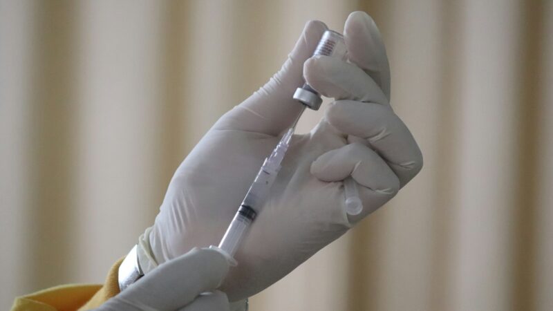 Person filling syringe with vaccine