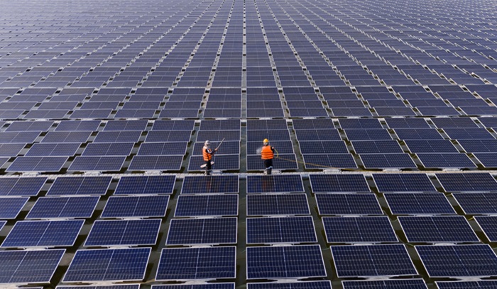 Professional workers clean and inspect solar panels on a floating buoy. Power plant with water